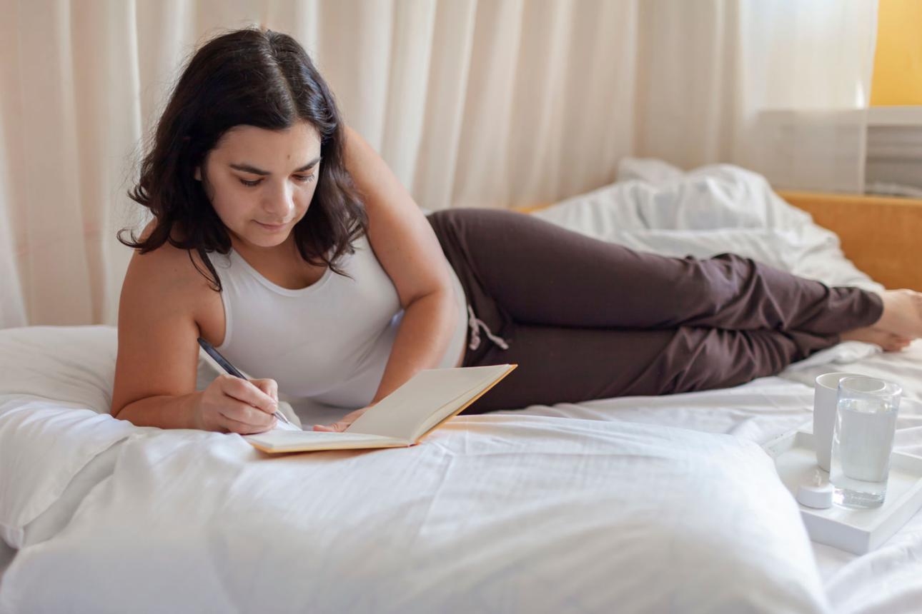 woman lying on the bed journaling